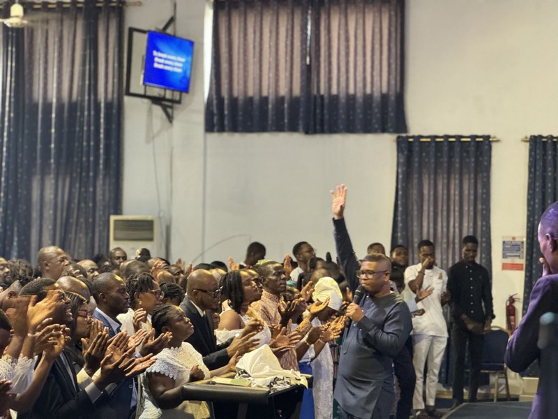 A hall full of worshippers with hands raised during a KGF gathering