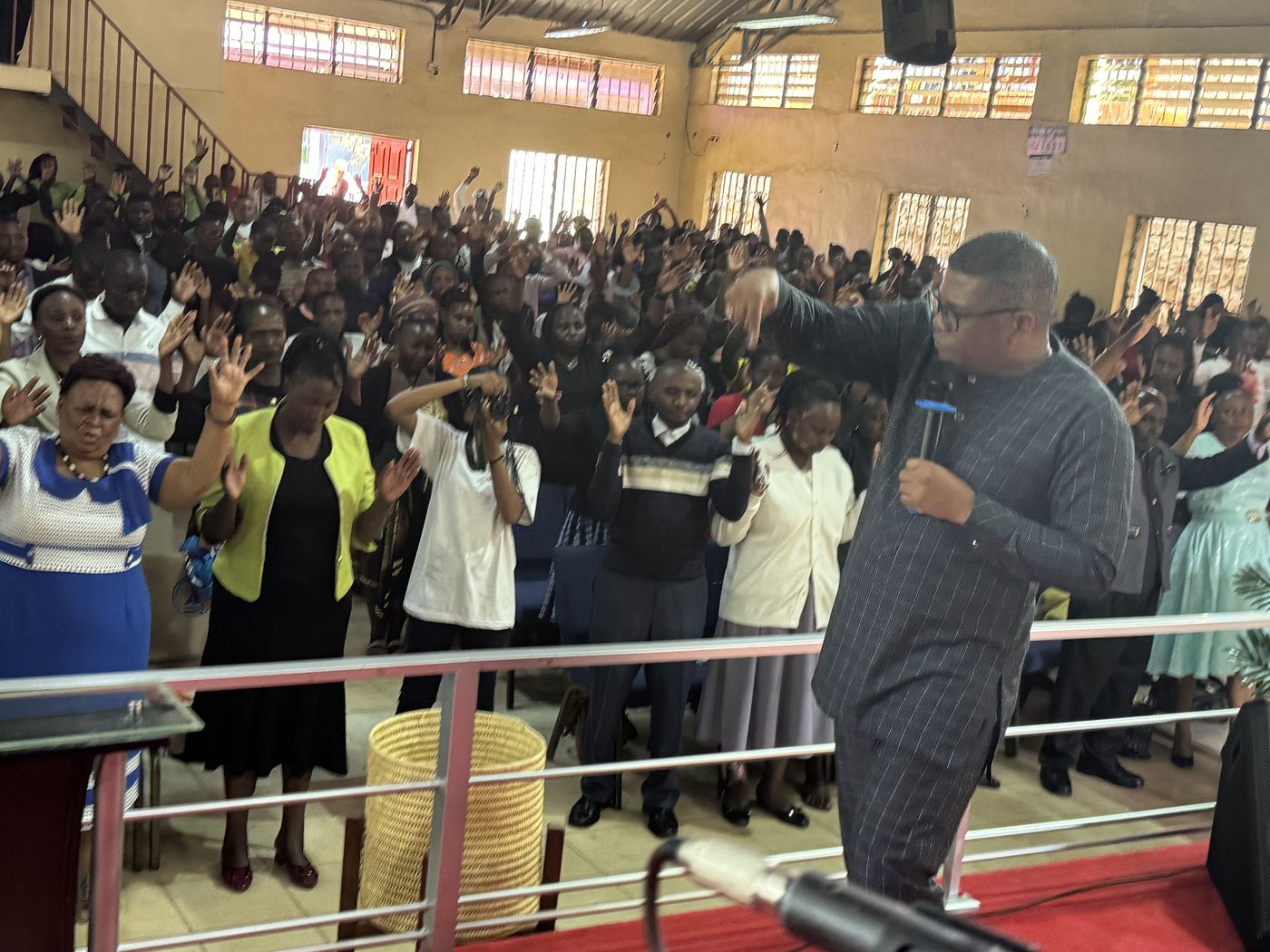 A preacher addressing a large crowd with hands raised