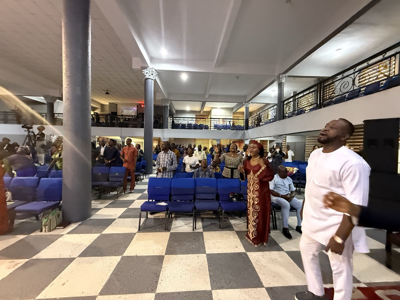 A hall gathering with a man in white addressing people